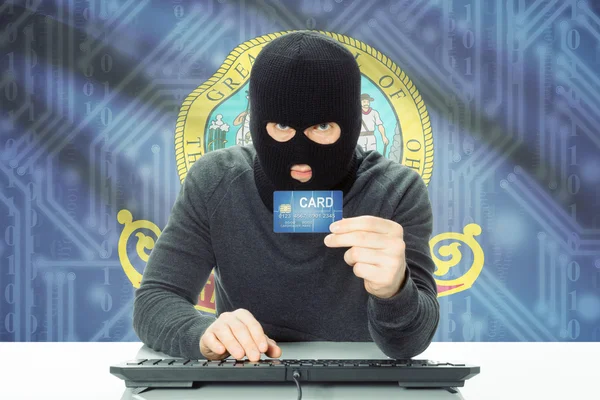 Hacker holding credit card and USA state flag on background - Idaho — Stock Photo, Image