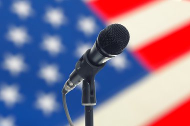 Microphone on stand with US flag on background - studio shot