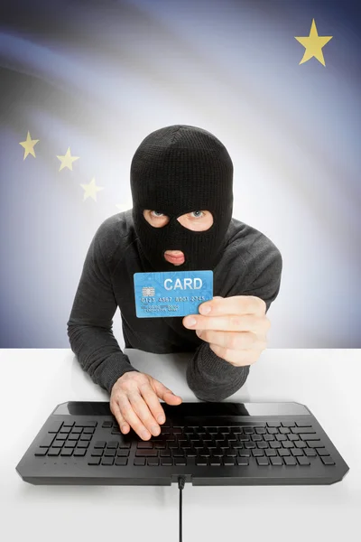 Hacker holding credit card with US state flag on background - Alaska — Foto Stock