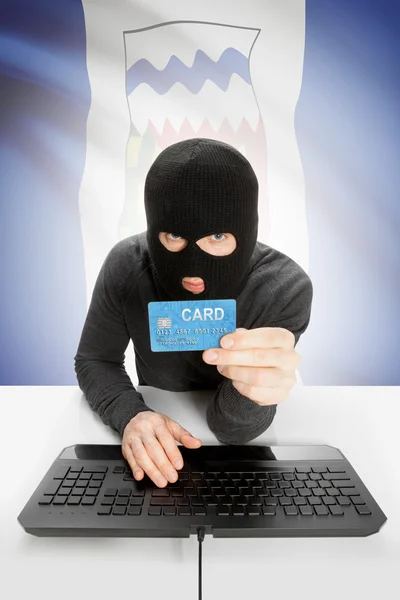 Hacker with credit card in hand and Canadian province flag on background - Northwest Territories — Stock Photo, Image