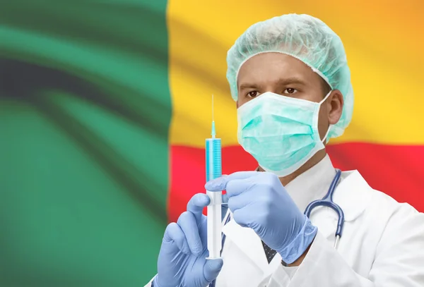 Médico con jeringa en las manos y la bandera en la serie del fondo - Benín —  Fotos de Stock