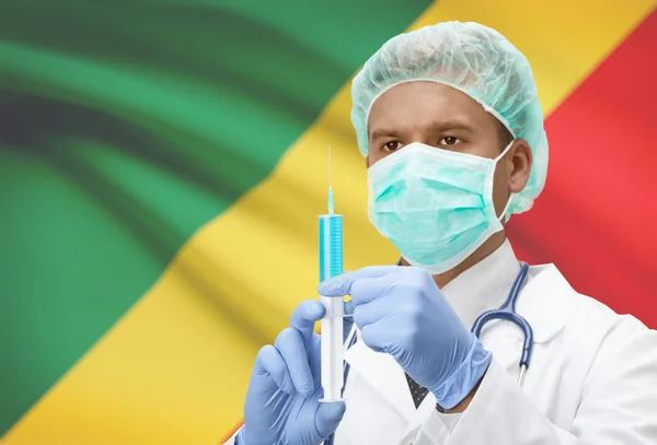 Doktor s injekční stříkačkou v ruce a vlajku na pozadí řady - Kongo-Brazzaville — Stock fotografie