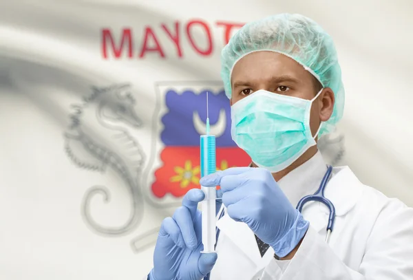 Doktor s injekční stříkačkou v ruce a vlajku na pozadí řady - Mayotte — Stock fotografie