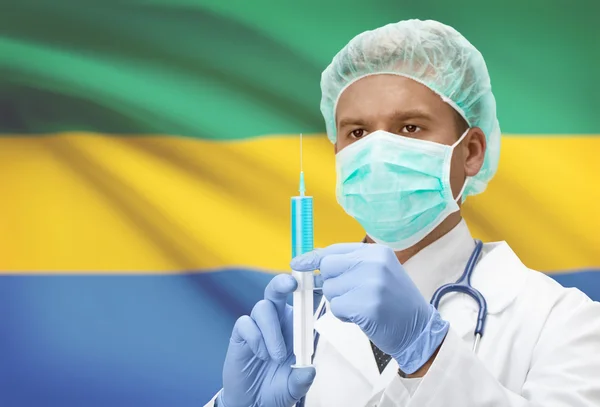 Médecin avec une seringue dans les mains et le drapeau sur la série de fond - Gabon — Photo