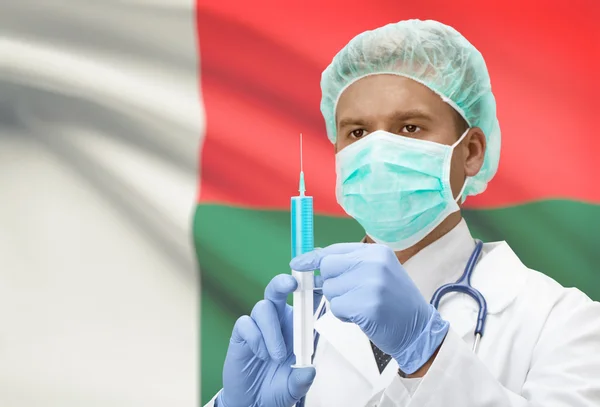 Médico com uma seringa nas mãos e bandeira na série de fundo - Madagascar — Fotografia de Stock