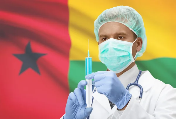 हातात सिरिंज आणि पार्श्वभूमी मालिकेवर ध्वज असलेले डॉक्टर गिनी-बिसाऊ — स्टॉक फोटो, इमेज