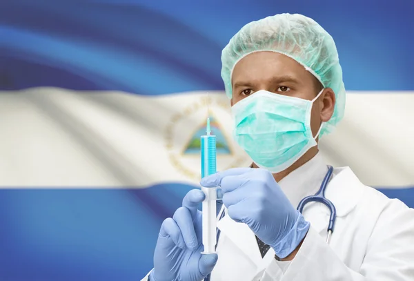 Médecin avec une seringue dans les mains et le drapeau sur la série de fond - Nicaragua — Photo