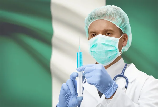 Médico con jeringa en las manos y la bandera en la serie de fondo - Nigeria —  Fotos de Stock