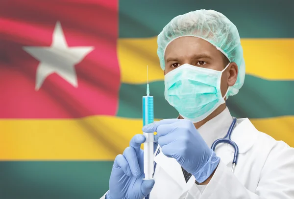 Médico con jeringa en las manos y la bandera en la serie del fondo - Togo — Foto de Stock