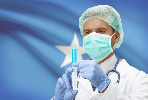 Médico con jeringa en las manos y la bandera en la serie de fondo - Somalia —  Fotos de Stock