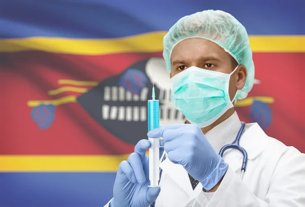 Doktor s injekční stříkačkou v ruce a vlajku na pozadí řady - Svazijsko — Stock fotografie