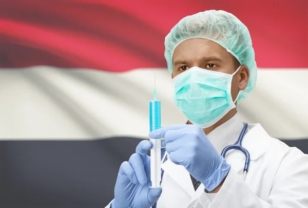 Médico con jeringa en las manos y la bandera en la serie del fondo - Yemen —  Fotos de Stock