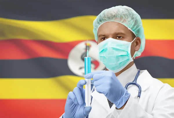 Médico con jeringa en las manos y la bandera en la serie de fondo - Uganda — Foto de Stock