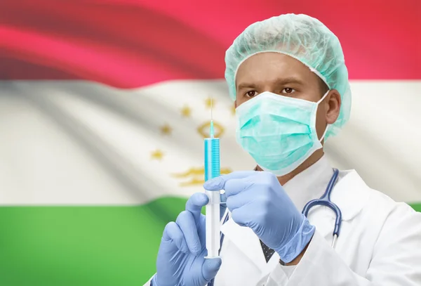 Médecin avec une seringue dans les mains et le drapeau sur la série de fond - Tadjikistan — Photo