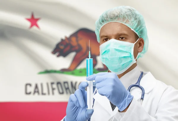 Docteur avec une seringue dans les mains et nous indique les drapeaux sur les séries de fond - Californie — Photo