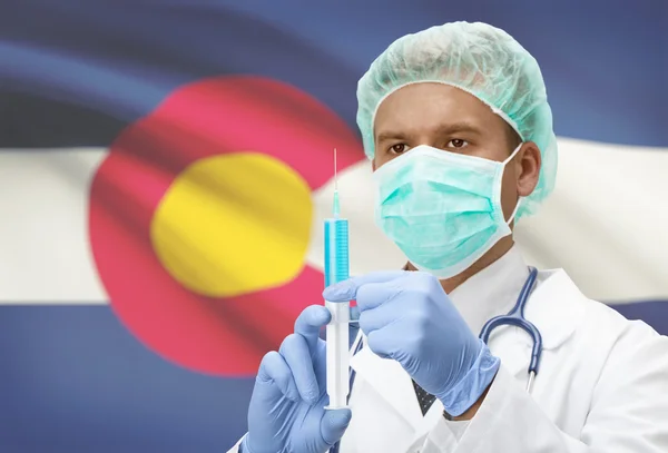 Docteur avec une seringue dans les mains et nous indique les drapeaux sur les séries de fond - Colorado — Photo