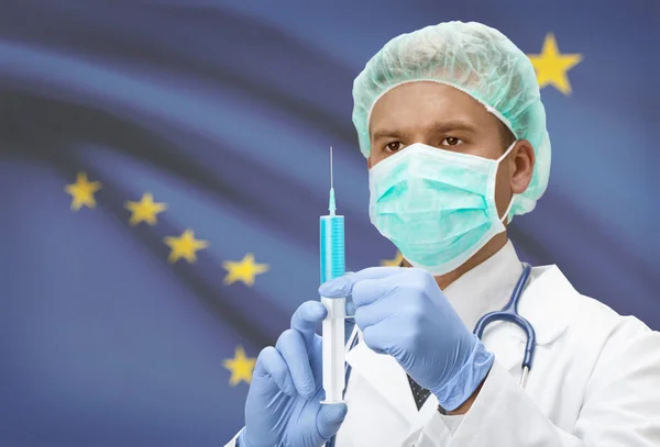 Doctor with syringe in hands and US states flags on background series - Alaska — Stock Photo, Image