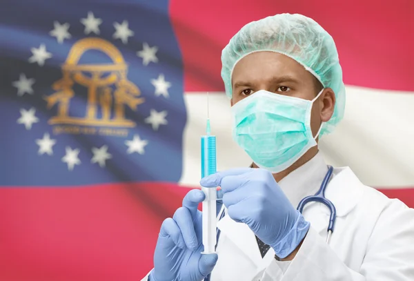 Docteur avec une seringue dans les mains et nous indique les drapeaux sur les séries de fond - Géorgie — Photo