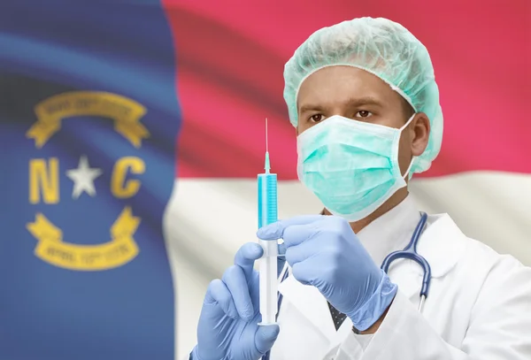 Doctor with syringe in hands and US states flags on background series - North Carolina — Stock Photo, Image