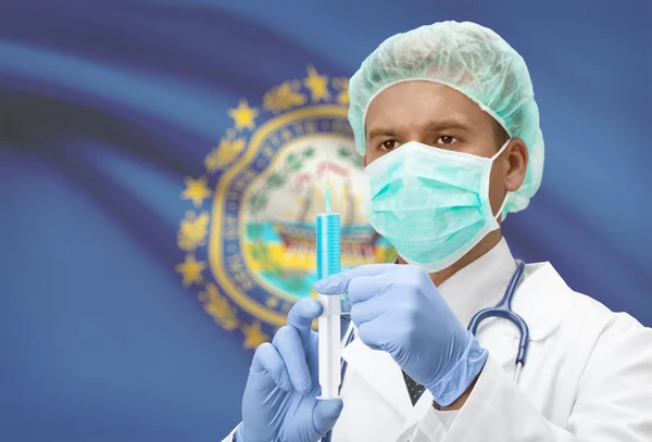 Docteur avec une seringue dans les mains et nous indique les drapeaux sur les séries de fond - New Hampshire — Photo