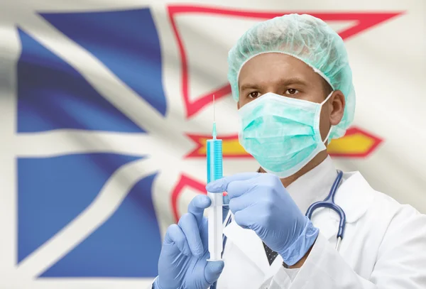 Lekarz z strzykawka w ręce i kanadyjskiej prowincji flagi na tle serii - Nowa Fundlandia i Labrador — Zdjęcie stockowe