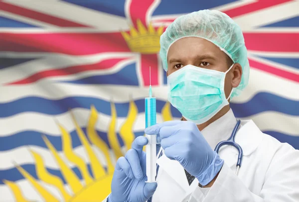 Médecin avec une seringue dans les mains et le drapeau de la province canadienne sur série de fond - Colombie-Britannique — Photo