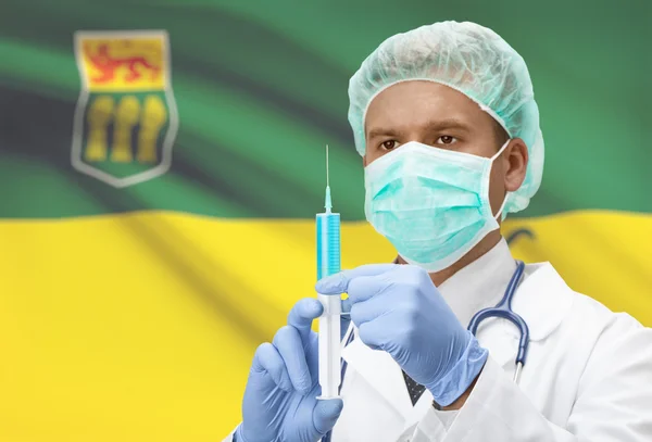 Médico con jeringa en las manos y la bandera de la provincia canadiense en serie de fondo - Saskatchewan —  Fotos de Stock