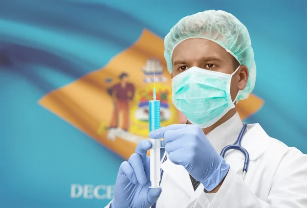 Docteur avec une seringue dans les mains et nous indique les drapeaux sur les séries de fond - Delaware Images De Stock Libres De Droits