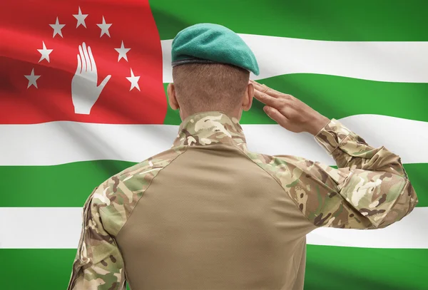 Dark-skinned soldier with flag on background - Abkhazia — Stock Photo, Image