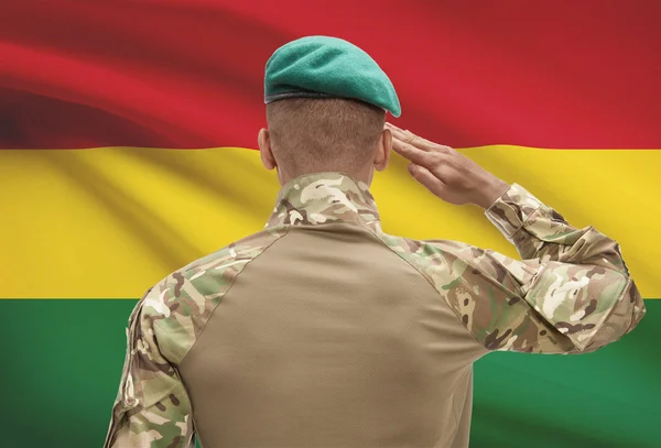 Dark-skinned soldier with flag on background - Bolivia — Stock Photo, Image