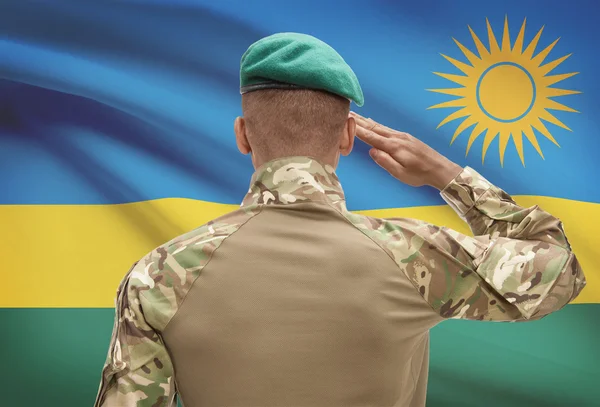 Dark-skinned soldier with flag on background - Rwanda — Stock Photo, Image