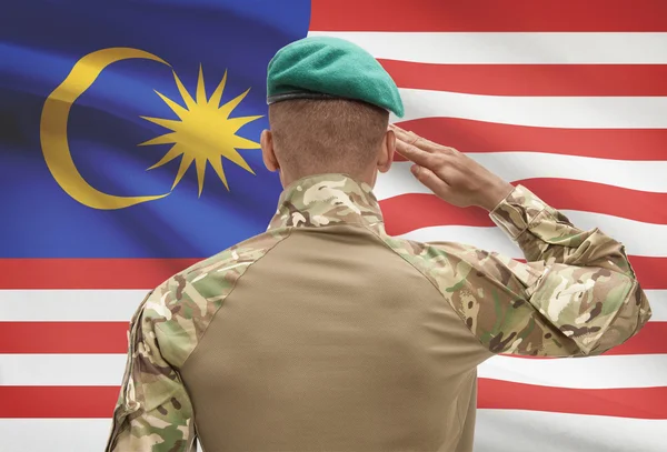 Dark-skinned soldier with flag on background - Malaysia — Stok Foto