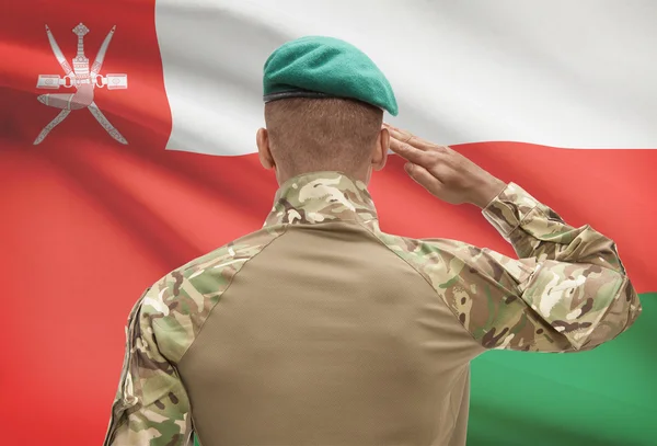 Dark-skinned soldier with flag on background - Oman — Stock Photo, Image