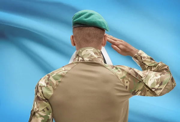 Dark-skinned soldier with flag on background - Saint Lucia — Stock Photo, Image