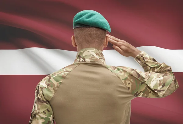Dark-skinned soldier with flag on background - Latvia