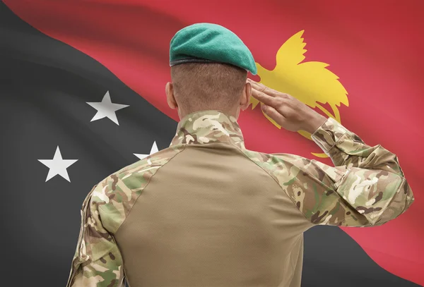 Dark-skinned soldier with flag on background - Papua New Guinea — Stock Photo, Image