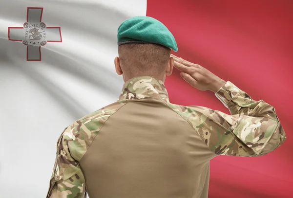 Piel oscura soldado con bandera sobre fondo - Malta — Foto de Stock