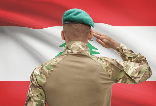 Dark-skinned soldier with flag on background - Lebanon — Stock Photo, Image