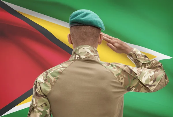 Dark-skinned soldier with flag on background - Guyana — Stock Photo, Image