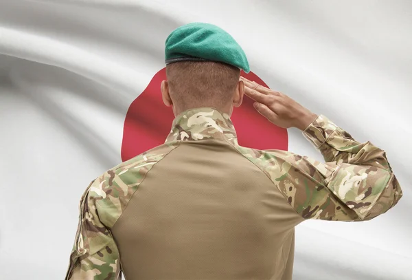 Dark-skinned soldier with flag on background - Japan — Stock Photo, Image
