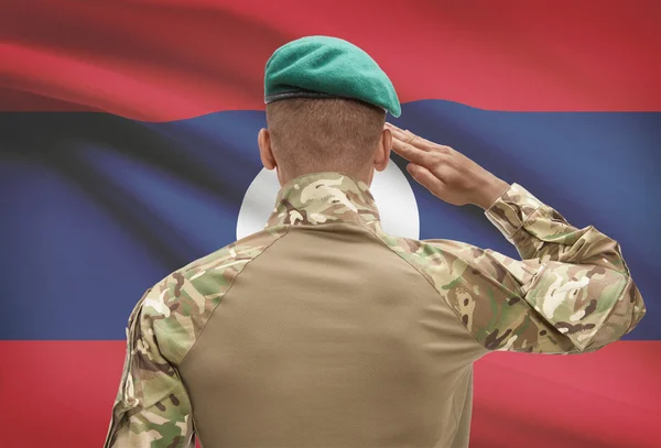Dark-skinned soldier with flag on background - Laos — Stock Photo, Image