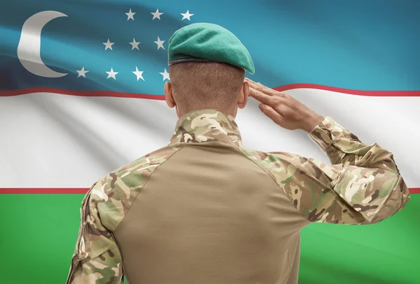 Dark-skinned soldier with flag on background - Uzbekistan — Stock Photo, Image
