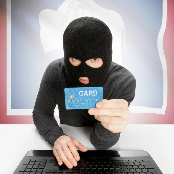 Hacker holding credit card with US state flag - Wyoming — Stock Photo, Image