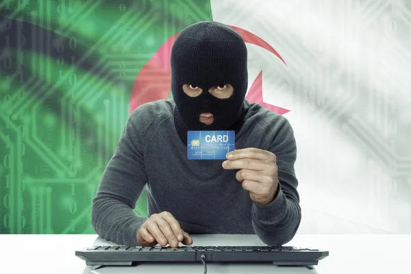 Dark-skinned hacker with flag on background holding credit card - Algeria — Stock Photo, Image