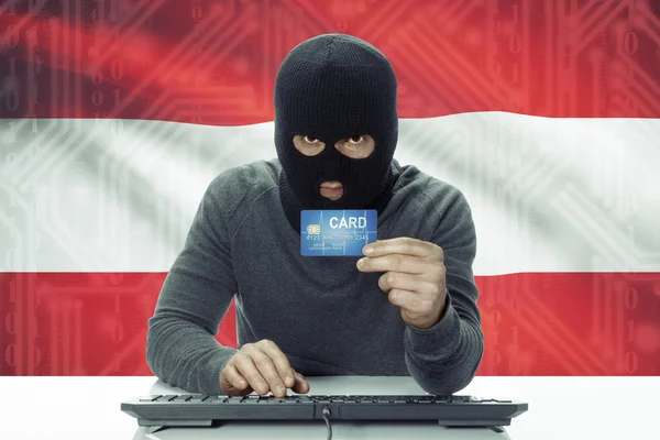 Dark-skinned hacker with flag on background holding credit card - Austria — Stock Photo, Image