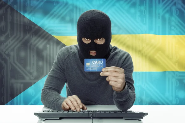 Dark-skinned hacker with flag on background holding credit card - Bahamas — Stock Photo, Image
