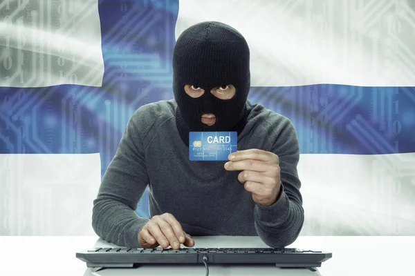 Dark-skinned hacker with flag on background holding credit card - Finland — Stock Photo, Image