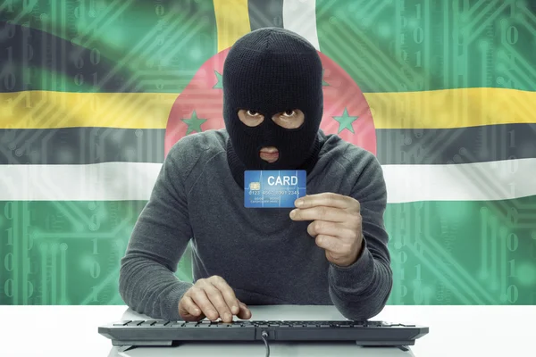 Dark-skinned hacker with flag on background holding credit card - Dominica — 图库照片