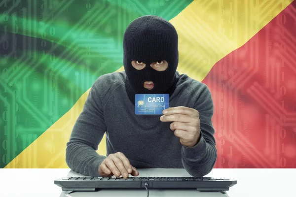 Dark-skinned hacker with flag on background holding credit card - Congo-Brazzaville — Stock fotografie