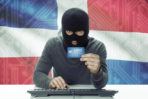 Dark-skinned hacker with flag on background holding credit card - Dominican Republic — Foto de Stock